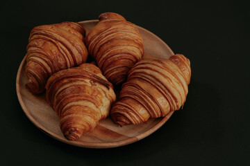 Croissants in a wooden bowl on dark background.