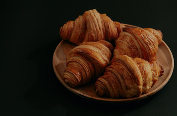 Croissants in a wooden bowl on dark background.