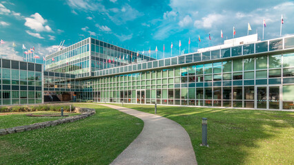 Modern low rise glass office building in business district and green lawn in inner yard timelapse hyperlapse