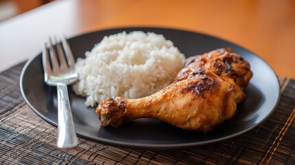 Delicious Grilled Chicken with Rice: A succulent grilled chicken leg is paired with fluffy rice and a sleek fork on a elegant dark plate, a tempting meal prepared for enjoyment.