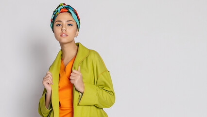 Portrait of a young woman with bright makeup and a fashionable headscarf.
