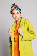 Portrait of a young woman with bright makeup and a fashionable headscarf.