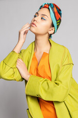 Portrait of a young woman with bright makeup and a fashionable headscarf.