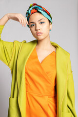 Portrait of a young woman with bright makeup and a fashionable headscarf.