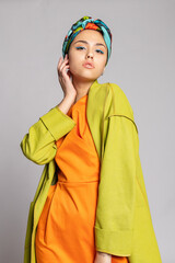 Portrait of a young woman with bright makeup and a fashionable headscarf.