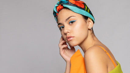 Portrait of a young woman with bright makeup and a fashionable headscarf.