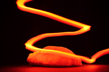 A loaf of bread rests on a black background, illuminated by dramatic rim lighting that highlights...