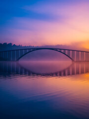 A stunning bridge over a tranquil lake at sunrise, with beautiful colors and a reflection.