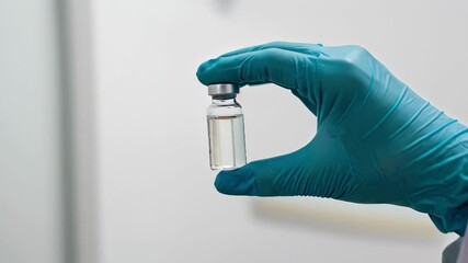 Vaccine in hand medical vial close up.  Holding small vaccine bottle shows clear liquid inside.  Healthcare worker displays vaccine in hand for immunization. - Powered by Adobe