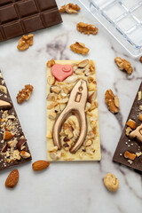 Novel artisanal white and dark chocolate bars with golden chocolates in the shape of tools and nuts glued on, ideal for gifts.
