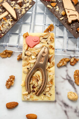 Novel artisanal white and dark chocolate bars with golden chocolates in the shape of tools and nuts glued on, ideal for gifts.