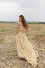 woman walking in golden dried grass field.