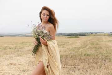 woman walking in golden dried grass field.