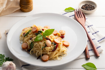 Stir Fried angel hair pasta With Dried Chili garlic and sliced sausage in white plate.