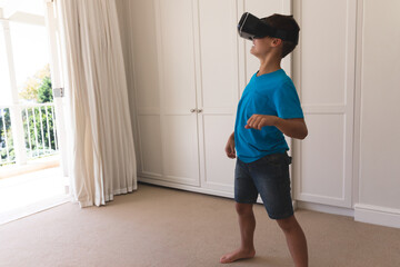Black virtual reality headset lying on carpet near sliding glass door to balcony with foliage