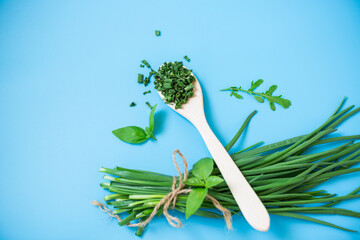 Top view of dried herbs and fresh green onions on blue background
