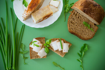 Traditional Ukrainian dish with lard and greens on a green background