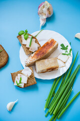 Classic Ukrainian snack with greens and homemade lard isolated on a blue background