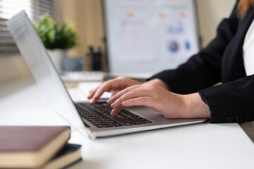 Businesswoman's hands typing text on laptop, close-up view