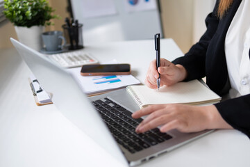 Businesswoman's hands taking notes on a notebook, close-up view
