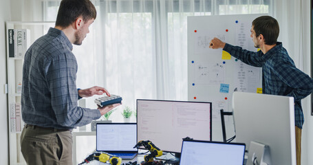 Team adult male engineer develop present AI robotics hand project at tech workspace. Artificial intelligence, collaboration support prototype development, robotic, debugging, machine learn, training.