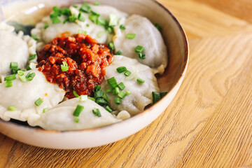 Traditional Polish dumplings on wooden table. Pierogi with meat and fried onions. Rustic home-cooked food. Delicious regional dish with fried topping. Tasty lunch meal. Homemade comfort cuisine.
