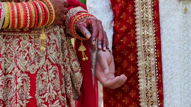 Wedding couple giving a hand to each other, dressed in traditional red Indian clothes, Elements of hindu wedding. Close up