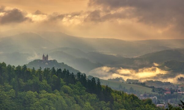 Summer landscape after a storm and beautiful light. Spring morning at sunrise with fog and historic chapel on the hill, hiking in the mountains.. Calvary over clouds in Banska Stiavnica, Slovakia. 