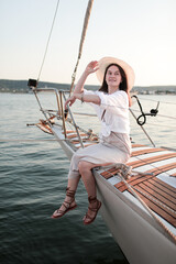 Beautiful young girl in a white shirt and hat on a yacht at sea in summer.