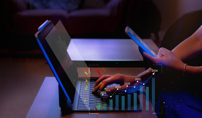 Businesswoman using laptop and smartphone at night to analyze AI driven data and financial growth from 2022 to 2026. Concept of digital transformation, marketing strategy, and fintech innovation.