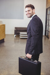 Naklejka premium Black leather briefcase resting on polished concrete floor in office lobby with white coffee table