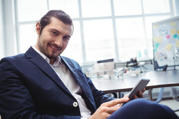 Man in business attire checking smartphone sitting at office desk by whiteboard notes, copy space
