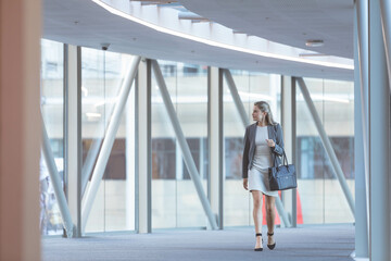 Glass walls and steel beams lining modern corridor under curved lights, copy space