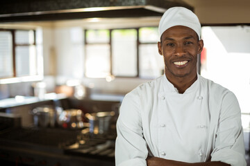 African American male chef in chef coat standing in restaurant kitchen beside stove, copy space