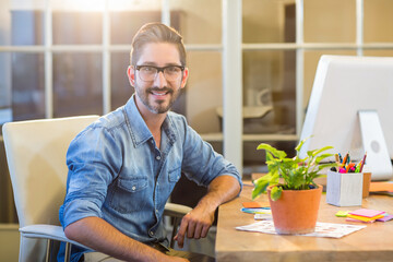 Man wearing denim shirt working at wooden desk with desktop monitor in office, copy space