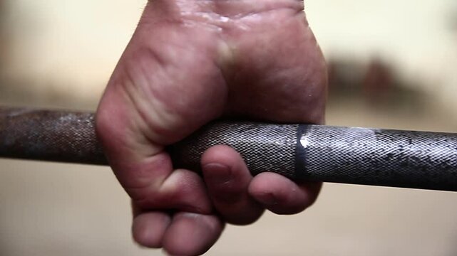 A hand, covered in white chalk, grips a knurled barbell tightly. This close-up shot emphasizes the preparation for heavy lifting, ideal for fitness, powerlifting