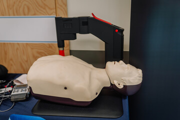 CPR training manikin on a table with an automated compression device, used in medical education and...