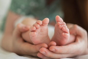 Happy family. Tiny newborn infant male or female baby feet on mother hands. Mother holding newborn child. Mom and her baby. Maternity tenderness parenthood new life concept. Handle with care