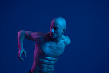 Focused man in motion, showcasing athleticism and strength, with vibrant blue lighting creating a...