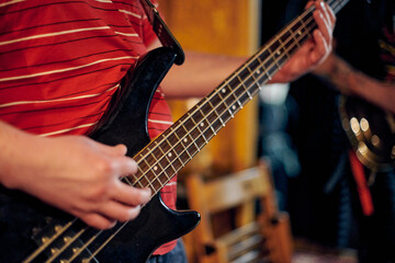 Focused view of musician hand playing bass guitar during performance, highlighting strings and...