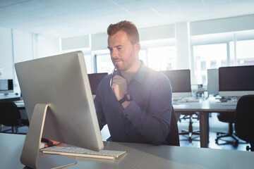 Modern office desk hosting desktop computer and wireless keyboard in bright window light