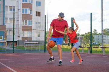 Father and daughter play basketball, fighting for the ball