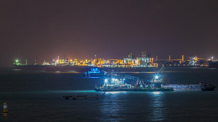 Obraz premium Singapore Marina Barrage with cargo ships waiting to enter one of the busiest ports in the world night timelapse, Singapore.