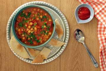 Homemade chickpea soup in a bowl. Pita bread and harissa.