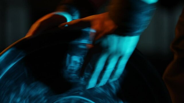 Close-up of an athlete's hands with wrist wraps grabbing a heavy weight plate. Dramatic blue and warm lighting creates a powerful, focused, and cinematic training atmosphere.