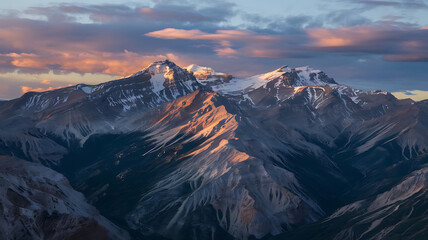 Sunset illuminates the snow-capped peaks of a majestic mountain range.