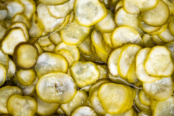 Close-up of sliced pickles submerged in brine, showcasing their texture, freshness, and appetizing...