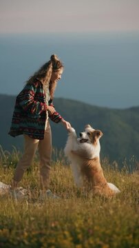 Girl and a border collie dog do a tricks in mountain and bay on background. A girl train her pet