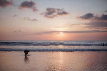 Serene Sunset Beach Scene Child Playing in the Ocean's Gentle Waves