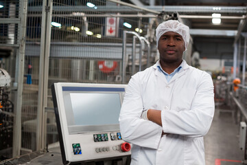 Mid adult African American man in lab coat inspecting touchscreen panel on plant floor, copy space